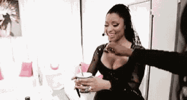 a woman in a black dress is sitting in a room holding a glass of water .