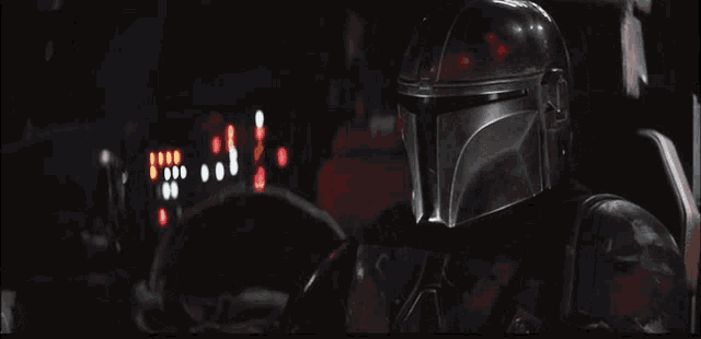 a man in a helmet is sitting in a dark room with a steering wheel .