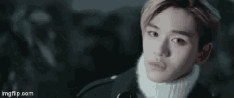 a close up of a young man wearing a black jacket and a white turtleneck .