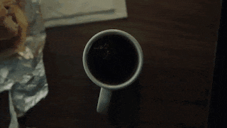 a cup of coffee with a bug in it on a table
