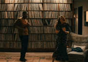 a man and a woman are dancing in a living room in front of a wall of books .