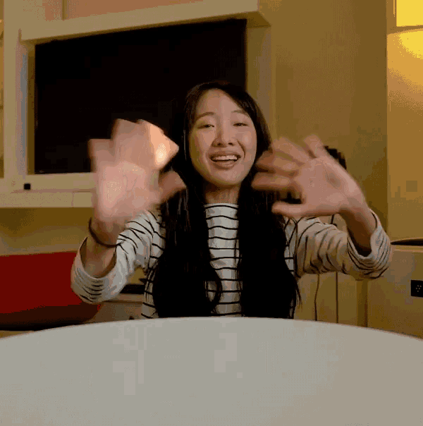 a woman sitting at a table with her arms outstretched and smiling