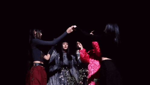 a group of women are holding hands in a circle in the dark