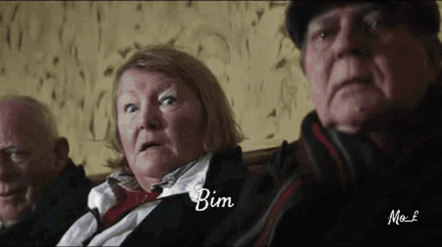 a group of older people are sitting next to each other and one of them has the word bim on her face .