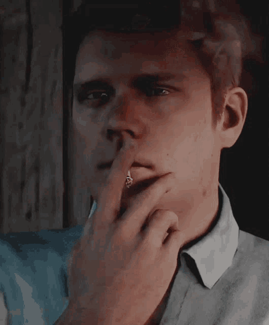 a man is smoking a cigarette while covering his mouth with his hand