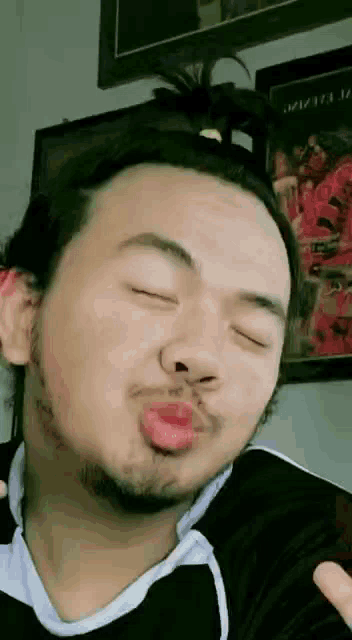 a man with a beard is blowing a kiss at the camera