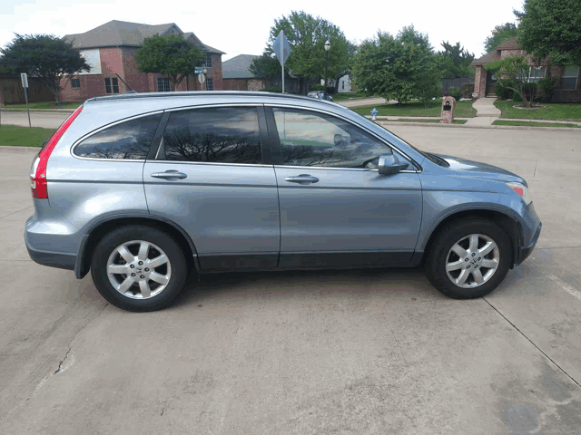 a blue honda crv is parked on a concrete driveway