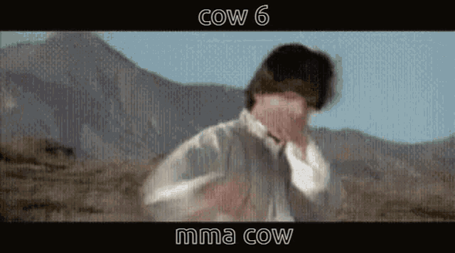 a man is standing in a field with mountains in the background and the words cow 6 and mma cow on the bottom