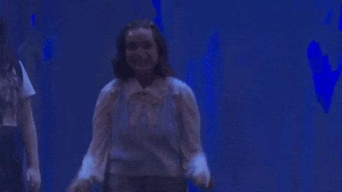 a person is standing in a dark room with a blue light behind them .