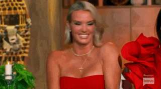 a woman in a red dress is smiling while sitting in front of a table .