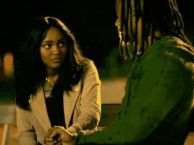 a man and a woman are holding hands and the woman is wearing a gold necklace