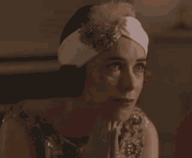 a woman wearing a white headband and a dress is looking at the camera .