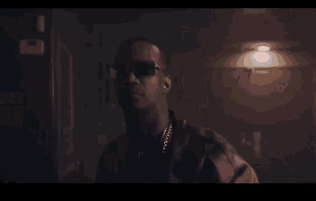 a man wearing sunglasses is standing in a dark room