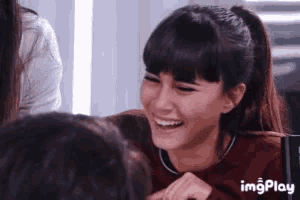 a woman with a ponytail is smiling and laughing while looking at another woman .
