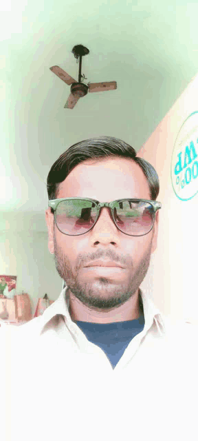 a man wearing sunglasses is standing in front of a wp sign