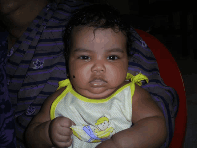 a baby is being held by a woman wearing a purple and white striped shirt
