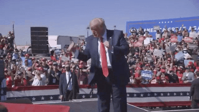 donald trump is dancing in front of a crowd at a campaign rally