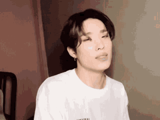 a young man is making a funny face while wearing a white t-shirt .