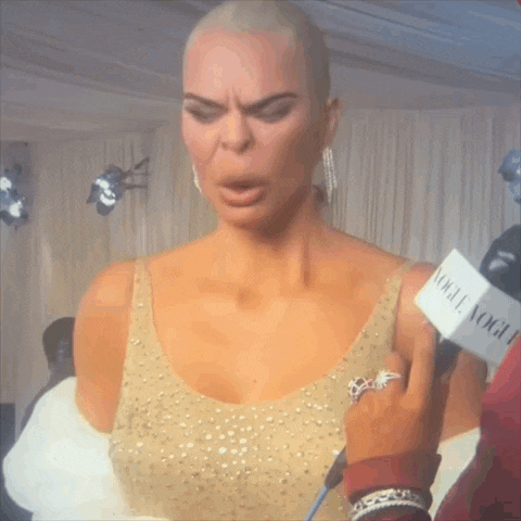 a woman in a gold dress is being interviewed by a person with a vogue microphone
