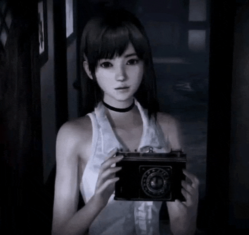 a girl in a white tank top is holding a camera in her hands .