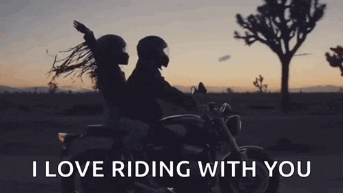 a man and woman are riding a motorcycle on a desert road .