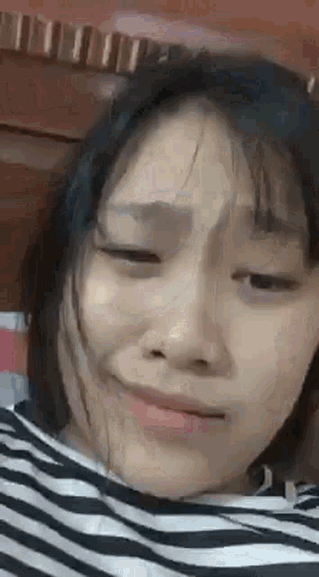a close up of a woman 's face with a striped shirt on making a funny face .