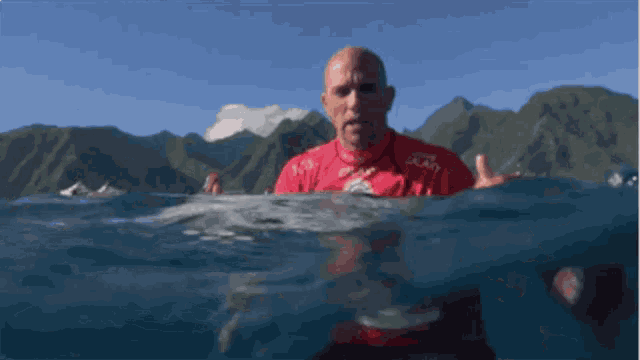 a man in a red shirt with the word galaxy on it is swimming in the ocean
