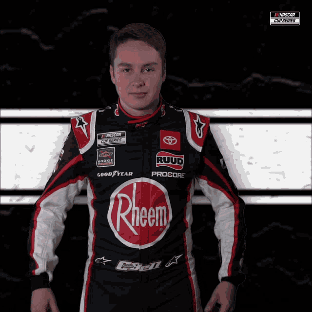 a race car driver is wearing a black and red outfit with the word rheem on the front