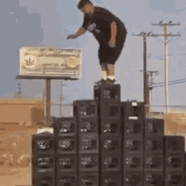 a man is jumping on top of a stack of crates .