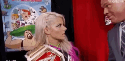 a woman in a wrestling ring is talking to a man in a suit and tie .