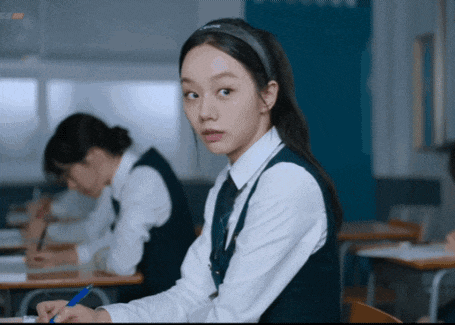 a girl wearing a headband that says ' lg ' on it sits in a classroom