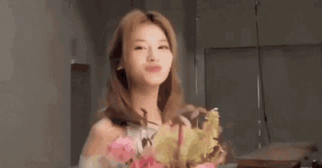a woman in a white dress is holding a bouquet of flowers .