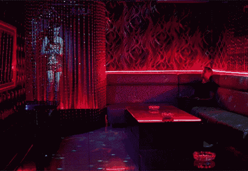 a woman sits on a couch in a dark room with red lights on the walls