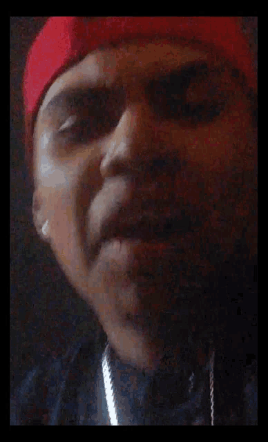 a close up of a man wearing a red hat and black shirt