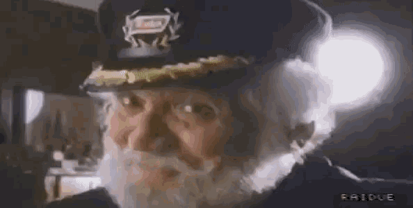 a man with a beard wearing a captain 's hat and glasses .