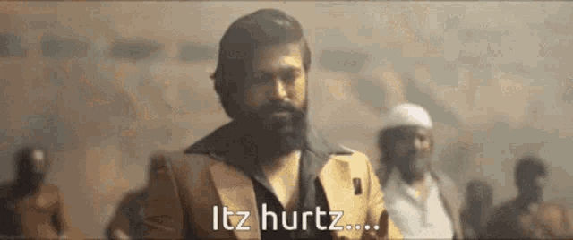 a man with a beard is standing in front of a crowd and says it 's hurtz ...