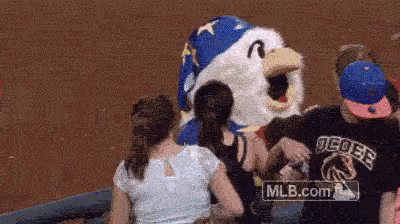 a mascot with the letter r on its head is surrounded by people