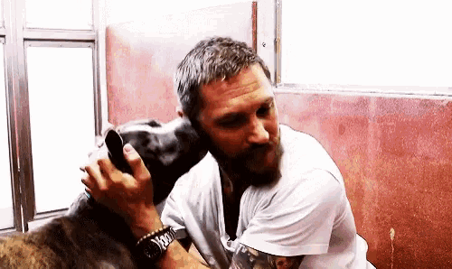 a man with a beard is sitting next to a dog .