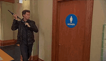 a man is holding a bat in front of a women 's restroom .