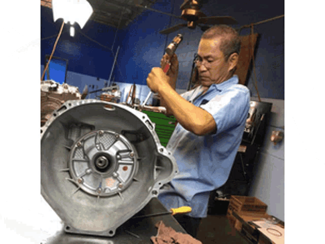 a man in a blue shirt is working on a car engine