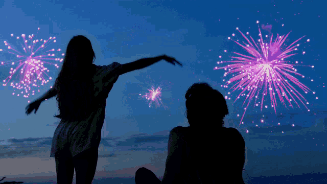 a man and a woman are watching fireworks in the sky
