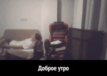 a man is laying on a couch next to a red and black chair