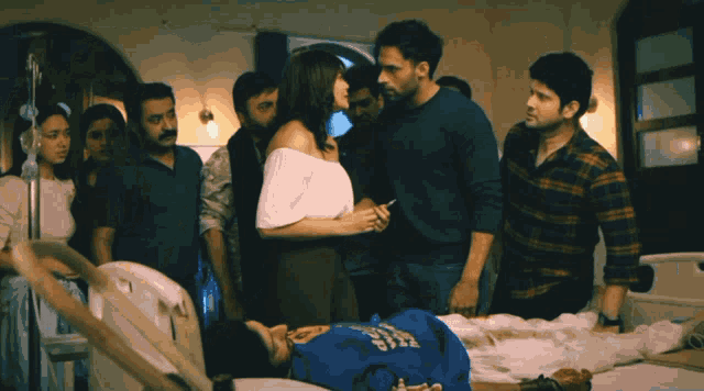 a group of people are standing around a man in a hospital bed