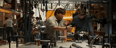two men are working on a project in a workshop with a sign that says " do not enter " on it