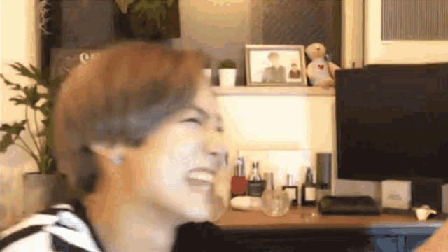 a man laughs in front of a computer monitor