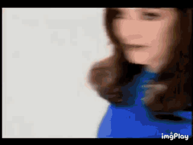 a blurry picture of a woman 's face with a blue shirt on