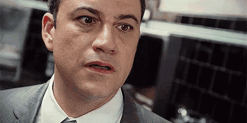a man in a suit and tie is looking at the camera .