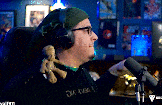 a man wearing headphones is holding a stuffed animal in front of a microphone