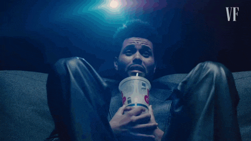 a man is sitting on a couch holding a cup that says mcdonalds on it