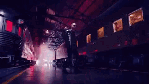 a man is smoking a cigarette while standing next to a train .